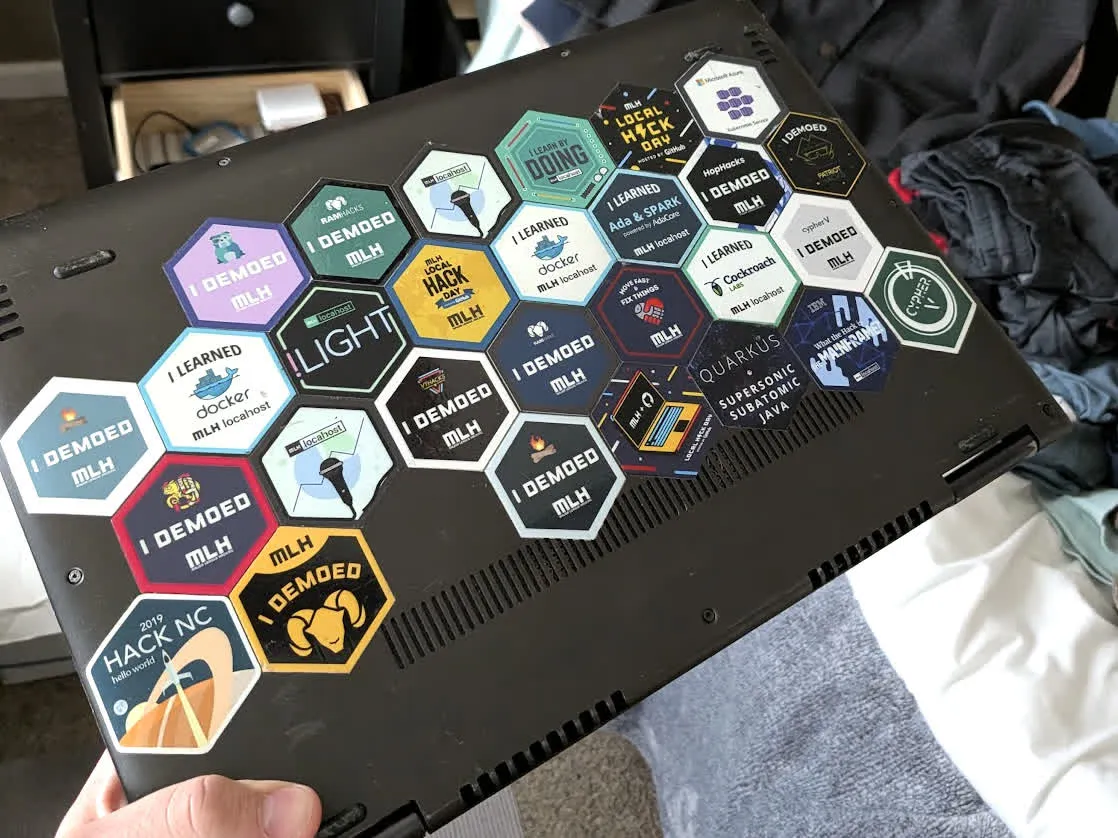 Picture of a laptop covered in hackathon stickers